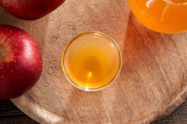 Arka planda taze meyve olan bir kase elma sirkesi.