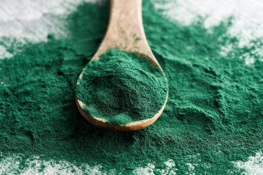Tahta kaşıkta spirulina tozunun yakın çekimi.