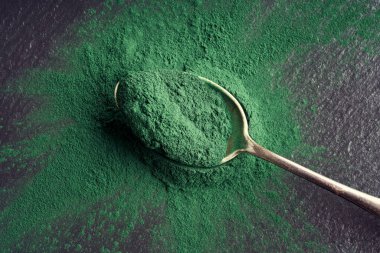 Koyu bir arka planda kaşığın üzerindeki alg tozu