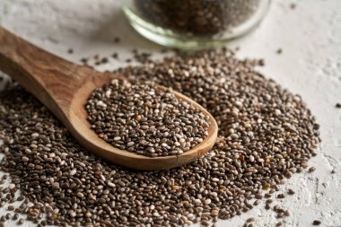 Beyaz arka planda tahta kaşıkta Chia tohumları, yakın plan.