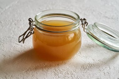 Beyaz arka planda cam bir kavanozda kemik suyu.