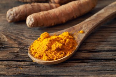 Taşra masasında zerdeçal tozu ve taze kök.