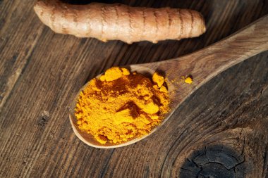 Tahta kaşıkta zerdeçal tozu ve taze kök, üst manzara.