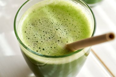 Beyaz bir masada yeşil meyve suyu.