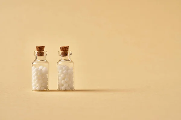 Two bottles of homeopathic remedies on beige background with copy space