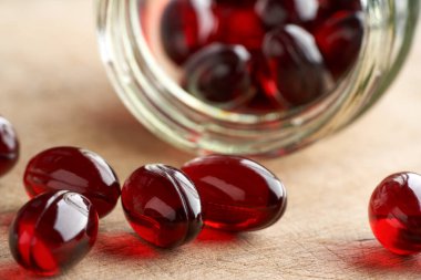 Kril yağı kapsülleri cam bir şişeden dökülüyor.