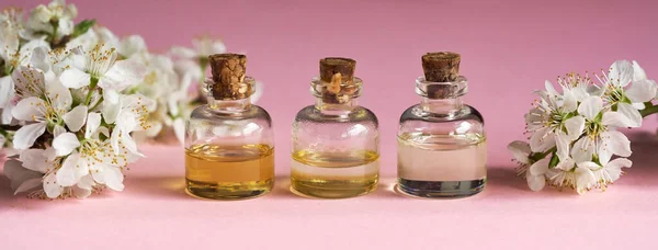 Три Пляшки Ефірної Олії Білими Квітами Рожевому Фоні — стокове фото