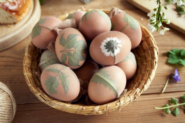 Paskalya yumurtalarının soğan kabuklarıyla ölmeye hazırlanması, yapraklarla süslenmiş.