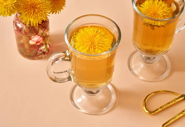 用新鲜蒲公英花装饰在淡黄色背景上的草茶 — 图库照片