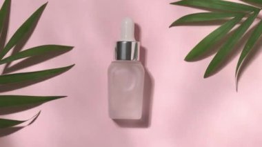 Pastel pembe arka planda, üzerinde ışıklar yanıp sönen tropikal palmiye yaprakları olan bir yağ şişesi.