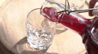 Ev yapımı siyah yaşlı şurubu şişeden shot bardağına dökülüyor.