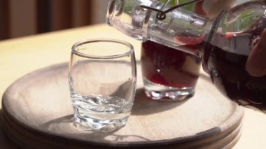 Ev yapımı siyah yaşlı şurubu şişeden bardağa dökülüyor, yavaş çekimde.