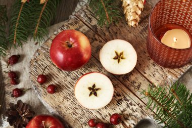 Two halves of a red apple with a star in the middle, with Christmas tree, dried rose hips and decoration