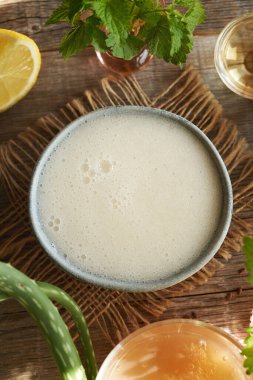 Top view of a bowl of DIY shampoo made with homemade flax seed gel, aloe vera, argan oil, apple cider vinegar, nettle and coco glucoside