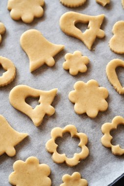 Shapes made of raw pastry dough on baking paper - preparation of Linzer Christmas cookies
