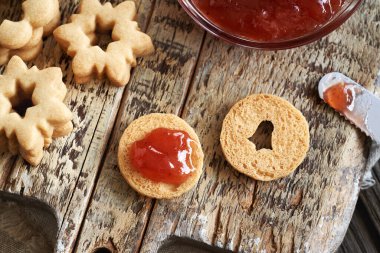 Ev yapımı Linzer Noel kurabiyelerini çilekli marmelatla doldurmak.