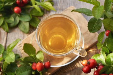 Gün ışığında taze böğürtlenli bir fincan gül kalçası çayı.