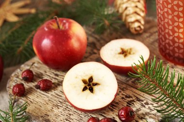 Yarısı taze kırmızı elma, ortasında bir yıldız, ladin ağacı ve Noel süslemesi var.