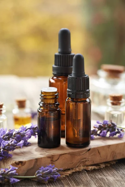 Sonbaharda açık bir masada taze lavanta çiçekleriyle üç kahverengi yağ şişesi.