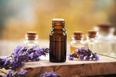 Açık havada taze açan lavanta bitkisi olan kahverengi bir yağ şişesi.