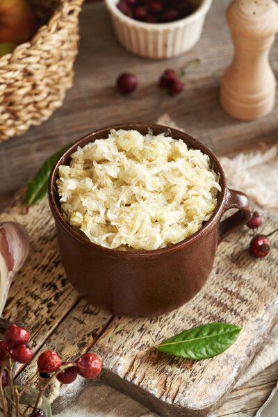 Fermented cabbage or sauerkraut in a clay pot on a wooden table