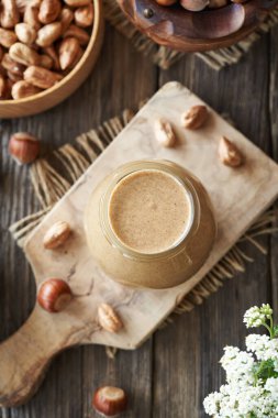 Ev yapımı fındık ezmesi, cam bir kavanozda, ahşap bir masada, üst tarafta.