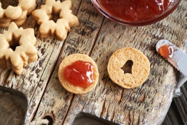 Ev yapımı Linzer Noel kurabiyelerini kırmızı çilekli marmelatla dolduruyorum.