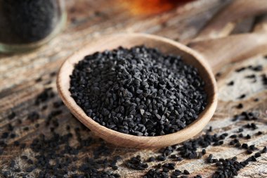 Tahta kaşıkta siyah kimyon ya da Nigella sativa tohumları. Sağlıklı besin desteği.