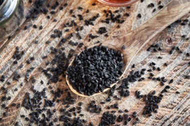 Tahta kaşıkta siyah kimyon ya da Nigella sativa tohumları, üst manzara.