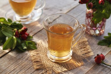 Tahta bir masanın üzerinde bir bardak gül suyu çayı.