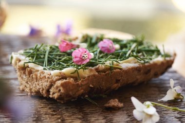 Bir dilim taze, yenilebilir bitkilerle bir dilim ekmek - karga sarımsak veya soğan otu, ve akciğer otu çiçekleri