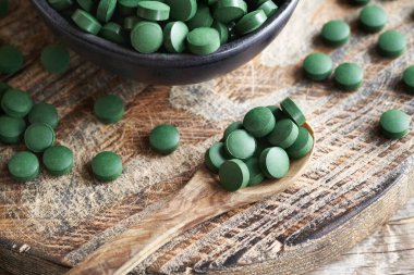 Yeşil spirulina alg tabletleri ya da tahta kaşıkta haplar.