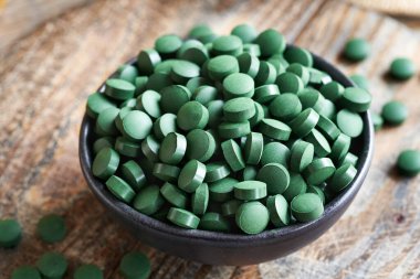 Tahta bir masadaki kasedeki alg tabletleri.