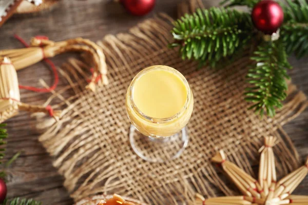 İçinde Noel ağacı dalları ve saman süsleri olan bir bardakta Eierkonyak.