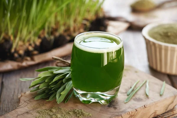 Bir bardak taze yeşil arpa suyu Taze yetişmiş bıçaklarla dolu bir masada