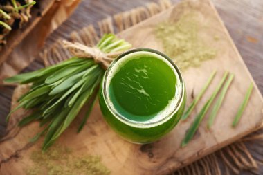 Taze yeşil arpa otu suyu ve masada arpa çimi yaprakları.