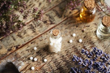 Cam şişede kurumuş otlar ve çiçeklerle birlikte Homeopatik ilaç hapları.
