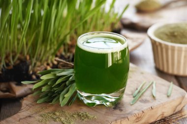 Taze yeşil arpa suyu ve tozu. Masanın üzerinde arpa otları var.