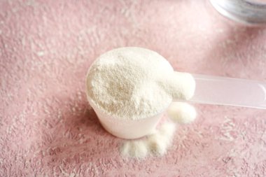 Plastik kepçedeki kolajen tozu pembe arka planda.