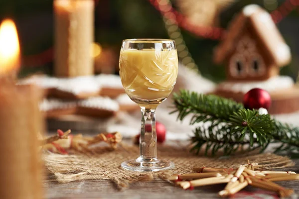 Masada cam bir fincanda mum ve Noel süslemeleri olan Eierkonyak.