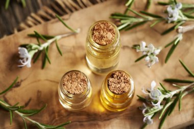 Üç şişe aromaterapi esaslı yağ ve biberiye dalları.