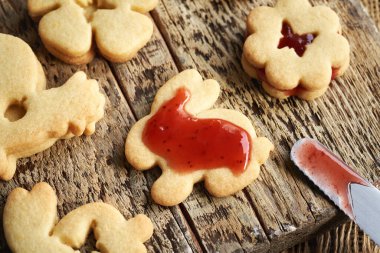 Ev yapımı Linzer Paskalya kurabiyesini çilekli marmelatla dolduruyorum.