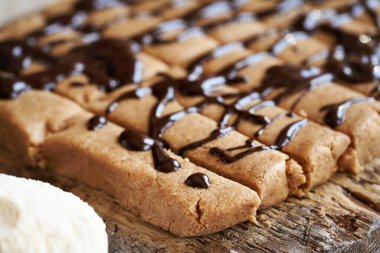 Sütlü protein tozundan yapılmış ev yapımı atıştırmalıklar, üstüne çikolata konmuş.