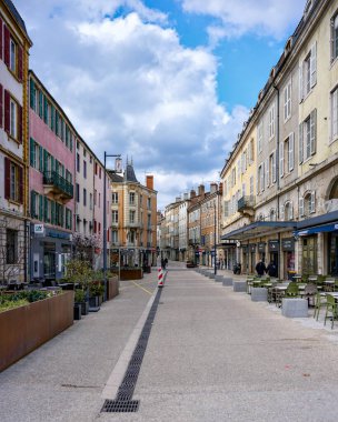Kafeleri ve bulutların altında boş yaya yolu olan eski, parlak bir şehir mimarisi.