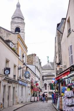 Fransa 'nın Montmartre bölgesindeki Sacre Coeur Bazilikası yakınlarındaki dar bir sokakta hediyelik eşya dükkanları ve yayalar..
