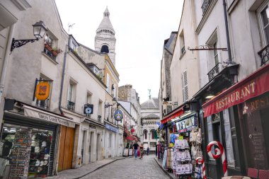 Montmartre bölgesindeki turist caddesinde hediyelik eşya dükkanları ve Paris 'teki Sacre Coeur Bazilikası manzarası.