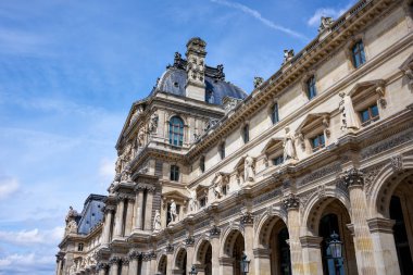 Detaylı mimarisi ve mavi gökyüzü yazı tipi olan tarihi Louvre binası