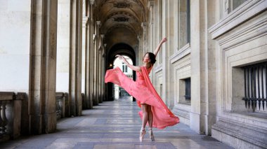 Kırmızı elbiseli balerin klasik Paris kemerlerinin altında zarifçe zıplıyor.