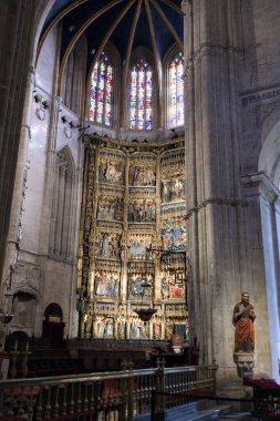 Gotik katedralin içindeki Oviedo Asturias İspanya 'daki renkli vitraylı pencereler altında İncil' e ait sahnelerle süslenmiş altın retablo sunağı. Fotoğraf 9 Eylül 2025 'te çekildi. Sadece editör kullanımı.