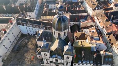 Etrafı tarihi çatılarla çevrili barok kilise kulesi ve güneşli koşullar altında su yolu ile çevrili uçan insansız hava aracı görüntüleri.